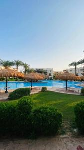 a large pool with straw umbrellas in a resort at Family Holiday 2 Bedroom Chalet with free Beach & Pool in Sharm, Egypt in Sharm El Sheikh