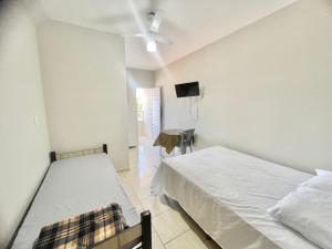 een slaapkamer met twee bedden en een flatscreen-tv bij Pousada Shalom Adonai-1 in Guarapari