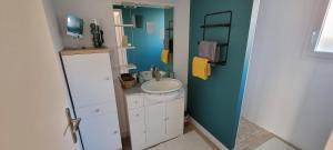een badkamer met een witte wastafel en een blauwe muur bij La maison du saule in Yves