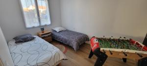 een kamer met twee bedden en een pingpongtafel bij La maison du saule in Yves
