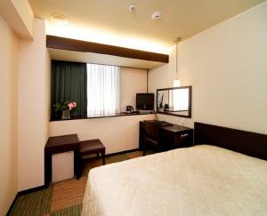 a hotel room with a bed and a desk and a window at Niigata City Hotel in Niigata