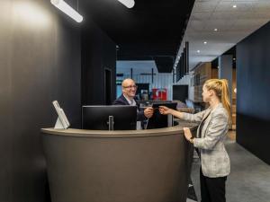 a woman standing in front of a counter in an office at ibis Duesseldorf Airport in Düsseldorf