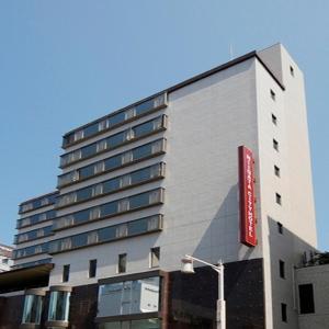 ein hohes Gebäude mit einem roten Schild darauf in der Unterkunft Niigata City Hotel in Niigata