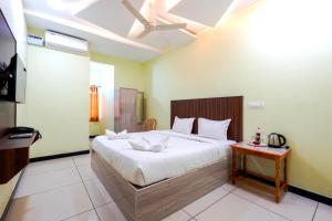 a bedroom with a large white bed and a table at Hotel Mini Escape Perungalathur in Chennai