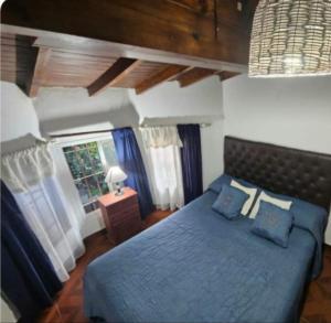 a bedroom with a blue bed and a window at Grace’s House, Ezeiza Airport in Monte Grande