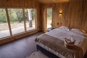 a bedroom with a large bed in a room with windows at Ecohotel Mauka in Pasto