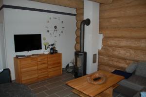 a living room with a flat screen tv and a wooden wall at Naturstamm Ferienhaus in Trassenheide