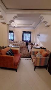 a large living room with couches and chairs in it at Appartement lumineux 2 pas à l'aéroport in Marrakech +10 photos