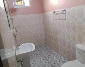 a bathroom with a white toilet and a sink at Maison meublée VERTE in Yaoundé +1 photo