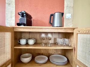 ein Regal mit Tellern, Gläsern und Weingläsern in der Unterkunft Le chateau d'Altheis in Dole