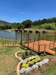 a wooden bridge over a body of water with flowers at Pousada reserva do J in Serra Negra