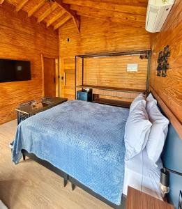 a bedroom with a blue bed in a wooden room at Pousada reserva do J in Serra Negra +44 photos