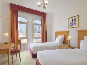 een hotelkamer met twee bedden en een raam bij Swissôtel Al Murooj Dubai in Dubai