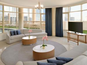 een woonkamer met twee banken en een tv bij Swissôtel Al Murooj Dubai in Dubai +202 foto's
