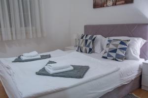 een wit bed met handdoeken en kussens erop bij Rooms Blanc in Pučišća