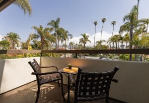 2 sedie e un tavolo sul balcone con palme di The Franciscan Hotel a Santa Barbara