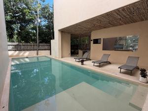 einen Pool mit 2 Stühlen und einem TV in der Unterkunft Calakmul Tulum in Cedro