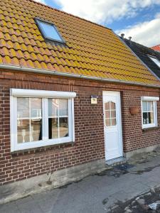 a brick house with an orange roof and a white door at Fischerhus in Fehmarn