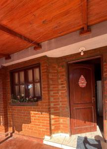 een stenen huis met een houten deur en ramen bij el rincon de roma in Puerto Iguazú