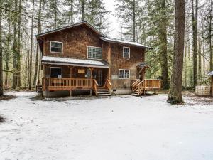 une cabane en rondins dans les bois avec de la neige au sol dans l'établissement River Dance Retreat - Meredith Lodging, à Welches