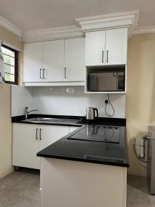una cucina con mobili bianchi e un forno a microonde di Crème de la crème Tiny Cottage a Durban