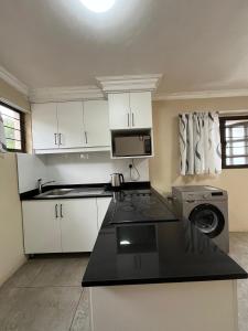 una cucina con mobili bianchi e lavatrice di Crème de la crème Tiny Cottage a Durban