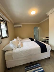 una camera da letto con un grande letto bianco in una stanza di Crème de la crème Tiny Cottage a Durban
