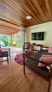 ein Wohnzimmer mit einem Bett und einem Fernseher in der Unterkunft Casa da Praia in Paraty