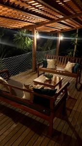 eine Terrasse mit zwei Bänken und einem Tisch auf einer Terrasse in der Unterkunft Casa da Praia in Paraty + 31 Fotos