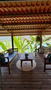 eine Holzterrasse mit zwei Bänken und einem Tisch in der Unterkunft Casa da Praia in Paraty