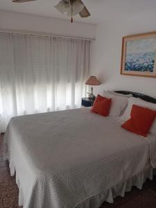 een slaapkamer met een groot wit bed met rode kussens bij peninsula fontemar in Punta del Este