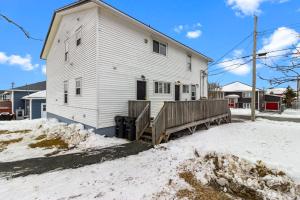 a white house with a wooden fence in the snow at Modern 2BR Suite Parking Laundry in Torbay