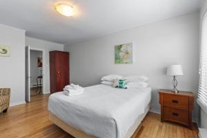 a white bedroom with a bed and a wooden floor at Modern 2BR Suite Parking Laundry in Torbay