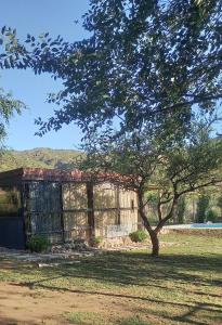 ein Gebäude auf einem Feld mit einem Baum im Vordergrund in der Unterkunft Lo de Nor - Refugio de Montaña in San Antonio de Arredondo