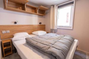 a bedroom with a large bed and a window at ZEcamping 4 étoiles 4km plage parc aquatique fitness dog friendly club enfant in Saint-Sulpice-de-Royan