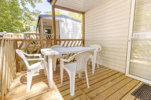 a porch with a white table and chairs at ZEcamping 4 étoiles 4km plage parc aquatique fitness dog friendly club enfant in Saint-Sulpice-de-Royan