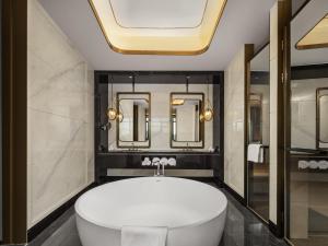 een badkamer met een groot wit bad en spiegels bij Swissotel Beijing Hong Kong Macau Center in Beijing +86 foto's