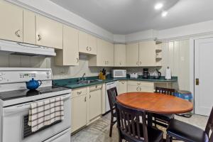 een keuken met witte kasten en een houten tafel bij Midstream Premier 2BR Wi-Fi Parking in St. John's