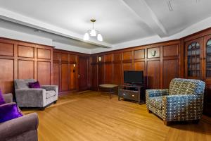 een woonkamer met houten lambrisering, stoelen en een tv bij Midstream Premier 2BR Wi-Fi Parking in St. John's