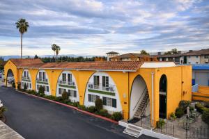 ein gelbes Gebäude mit weißen Fenstern und einer Straße in der Unterkunft Granada Inn in Santa Clara