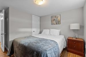 ein weißes Schlafzimmer mit einem Bett und einem Nachttisch in der Unterkunft Stylish 2BR WiFi Parking MUN Walk in St. John's