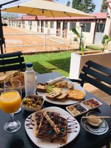 a table topped with plates of food and a glass of orange juice at Forsen Kerkouen in Kerkouene