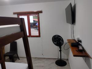 een kamer met een ventilator, een televisie en een bureau bij Finca Hotel Rancho Cattleya in Estación El Salto