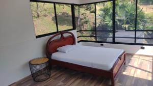 een slaapkamer met een bed met een stoel en ramen bij Finca Hotel Rancho Cattleya in Estación El Salto +22 foto's