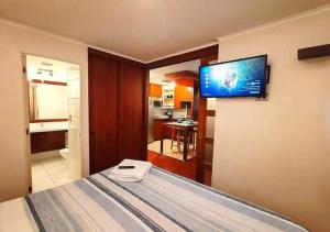 een slaapkamer met een bed en een flatscreen-tv aan de muur bij Apart Merced Home in Santiago