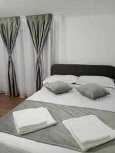 a large bed with white sheets and pillows on it at Apartament Adelina Borsa in Borşa
