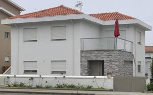 ein weißes Haus mit einem roten Regenschirm davor in der Unterkunft Enjoy Esmoriz in Esmoriz