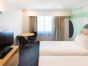een hotelkamer met twee bedden en een tafel bij ibis Styles Sydney Central in Sydney
