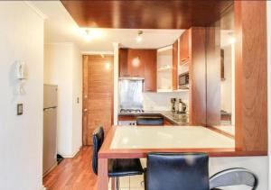 een keuken met houten kasten en een aanrechtblad bij Apart Merced Home in Santiago