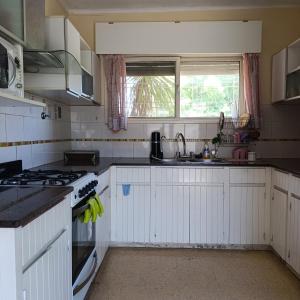 a kitchen with white cabinets and a sink and a stove at Alquiler temporal Casa céntrica in La Falda +3 photos